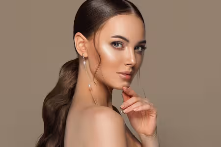 A beautiful woman is resting her fingertips on her face