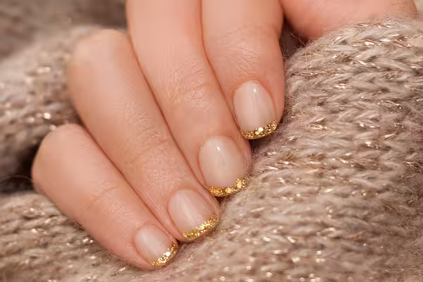 A woman's hand with a simple nail design holds a piece of sweater fabric