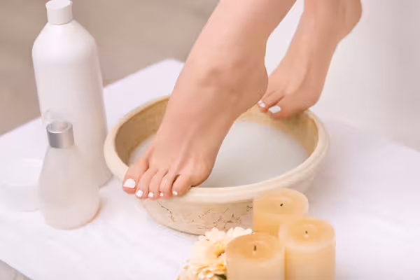 A woman's feet rest in a bowl filled with soapy water